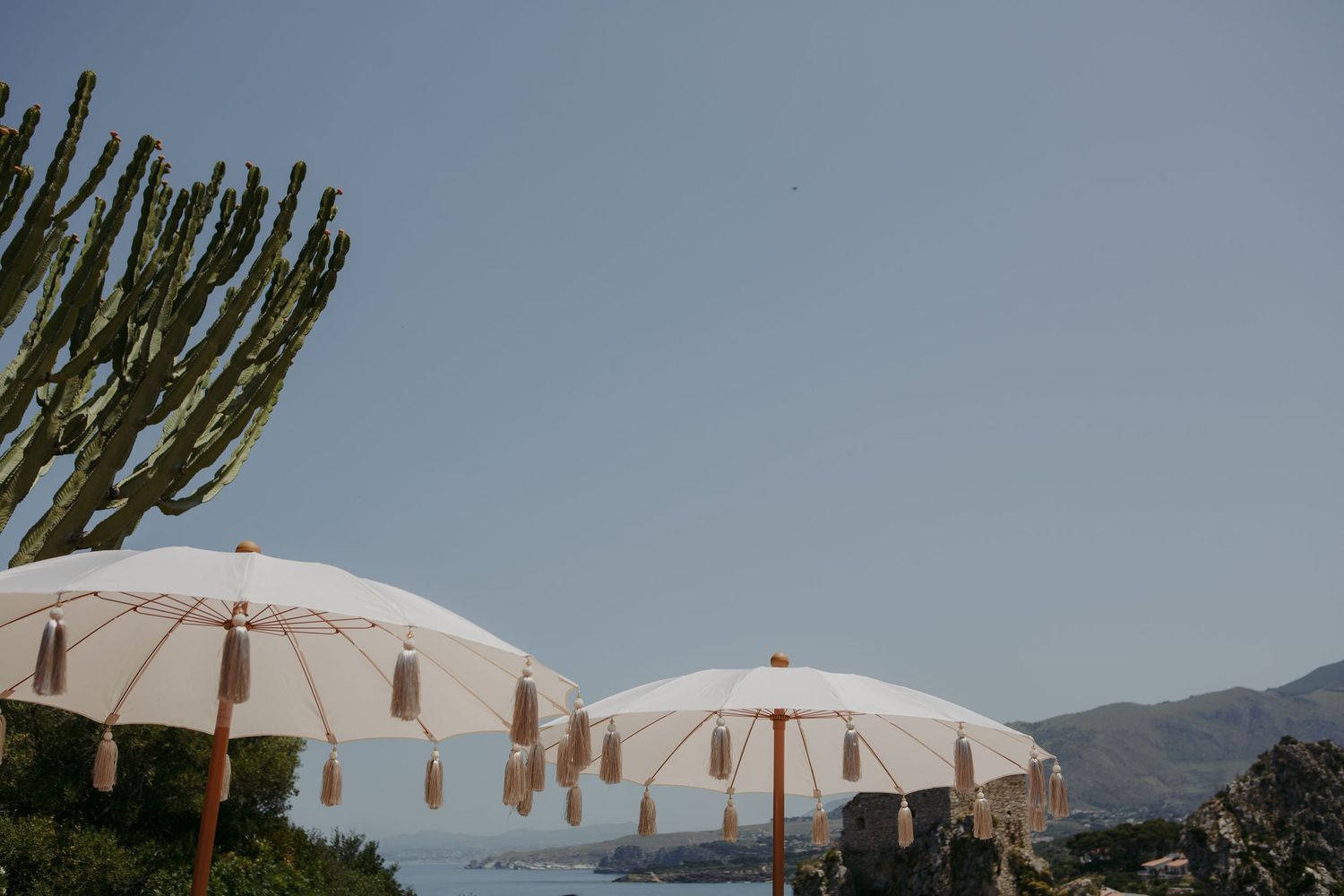 White umbrellas line up against a scenic mountain backdrop at an outdoor event venue during daytime.