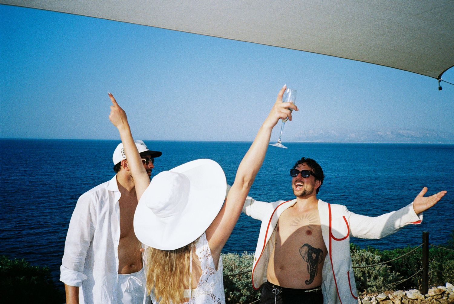 A collage of joyful people with raised arms celebrating outdoors against a blue ocean backdrop.