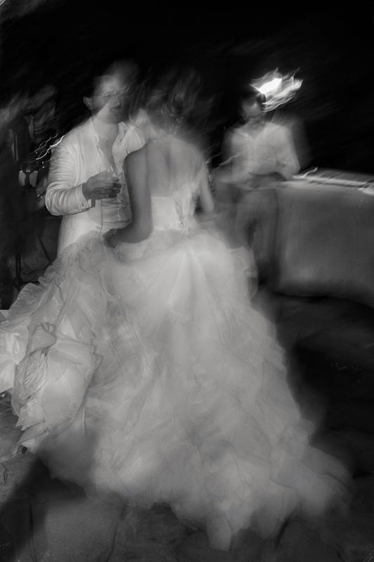 Artistic motion blur photograph of dancers in formal attire creating an ethereal effect in black and white.