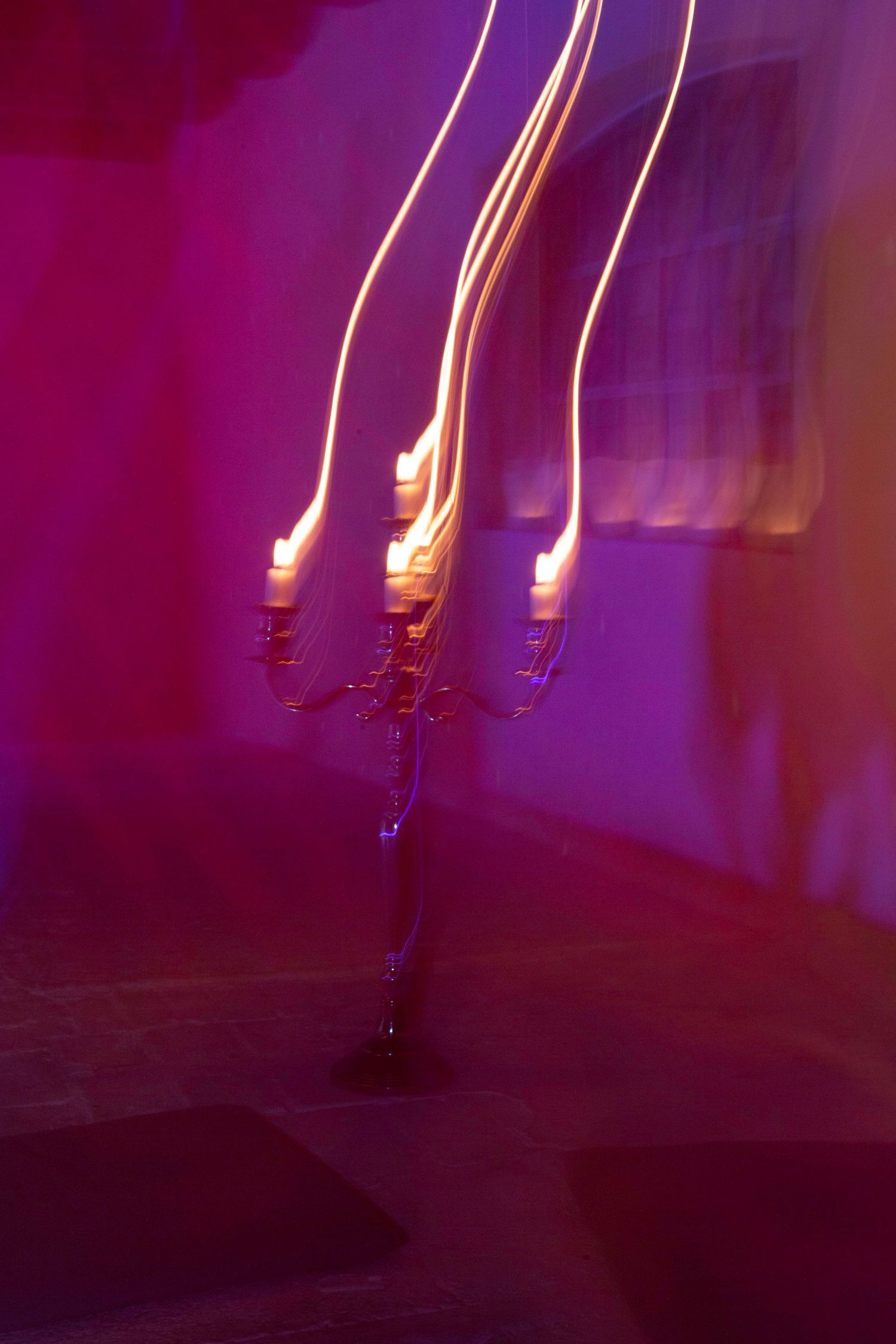 A candelabra with glowing candles casts a warm glow against a purple-tinted atmospheric background.