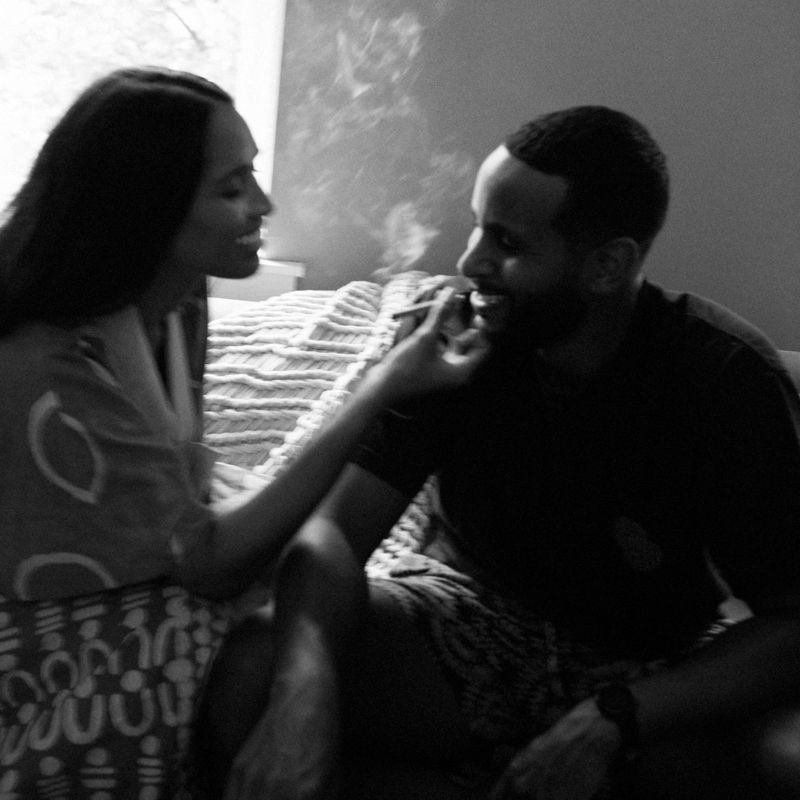 Black and white photo of a couple sharing an intimate moment, woman touching mans face while sitting together indoors.