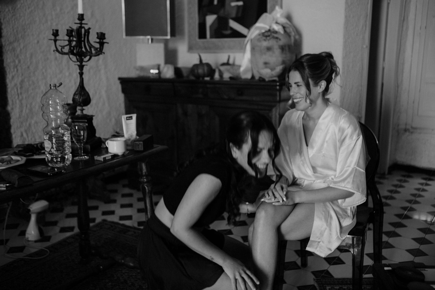 Black and white photo collage showing candid moments of people in a vintage interior setting with chandeliers.