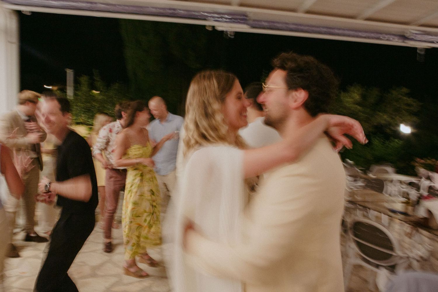 Couples dancing together at an outdoor evening celebration with blurred motion effect.