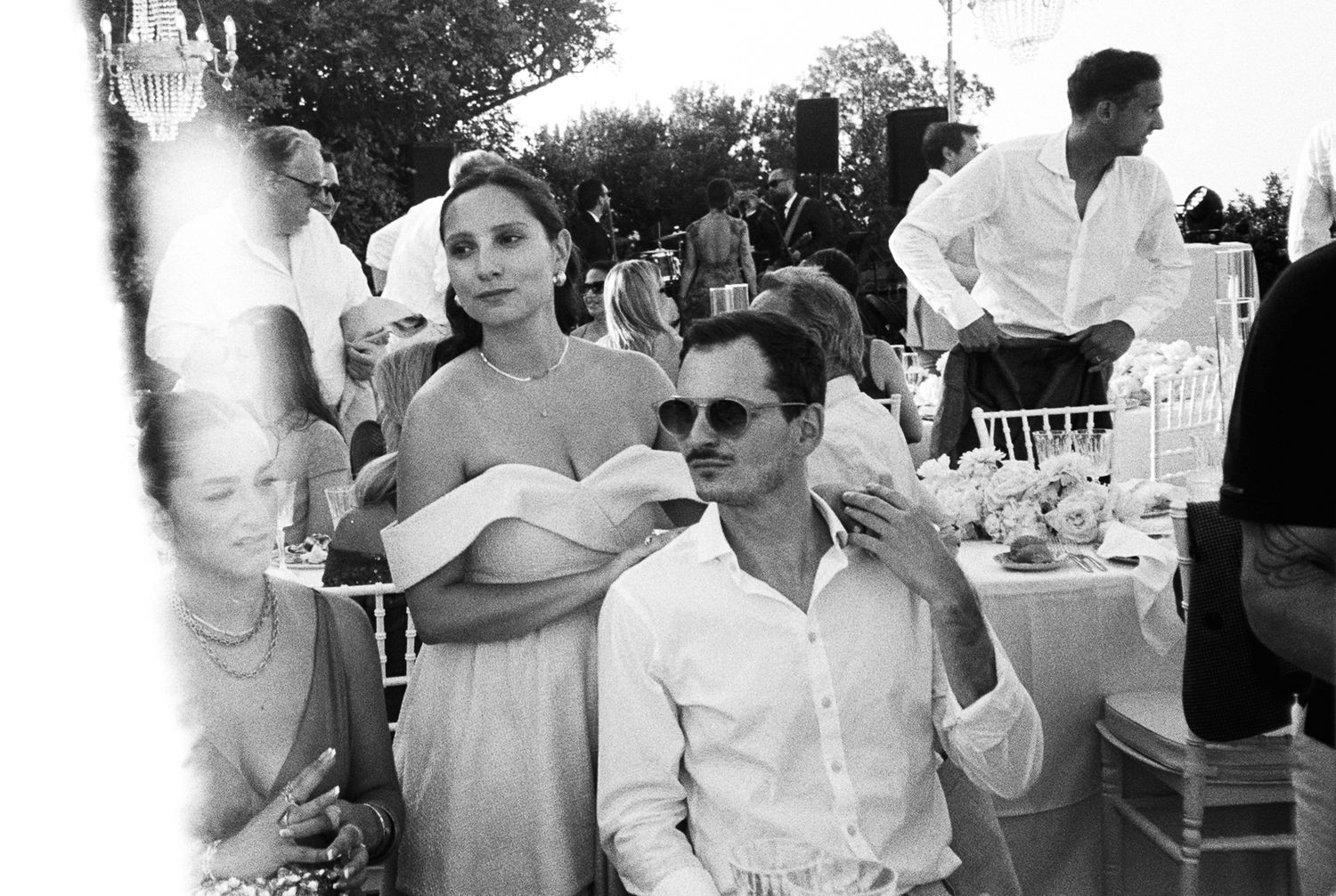 A black and white panoramic photo showing people enjoying an outdoor celebration or party setting.