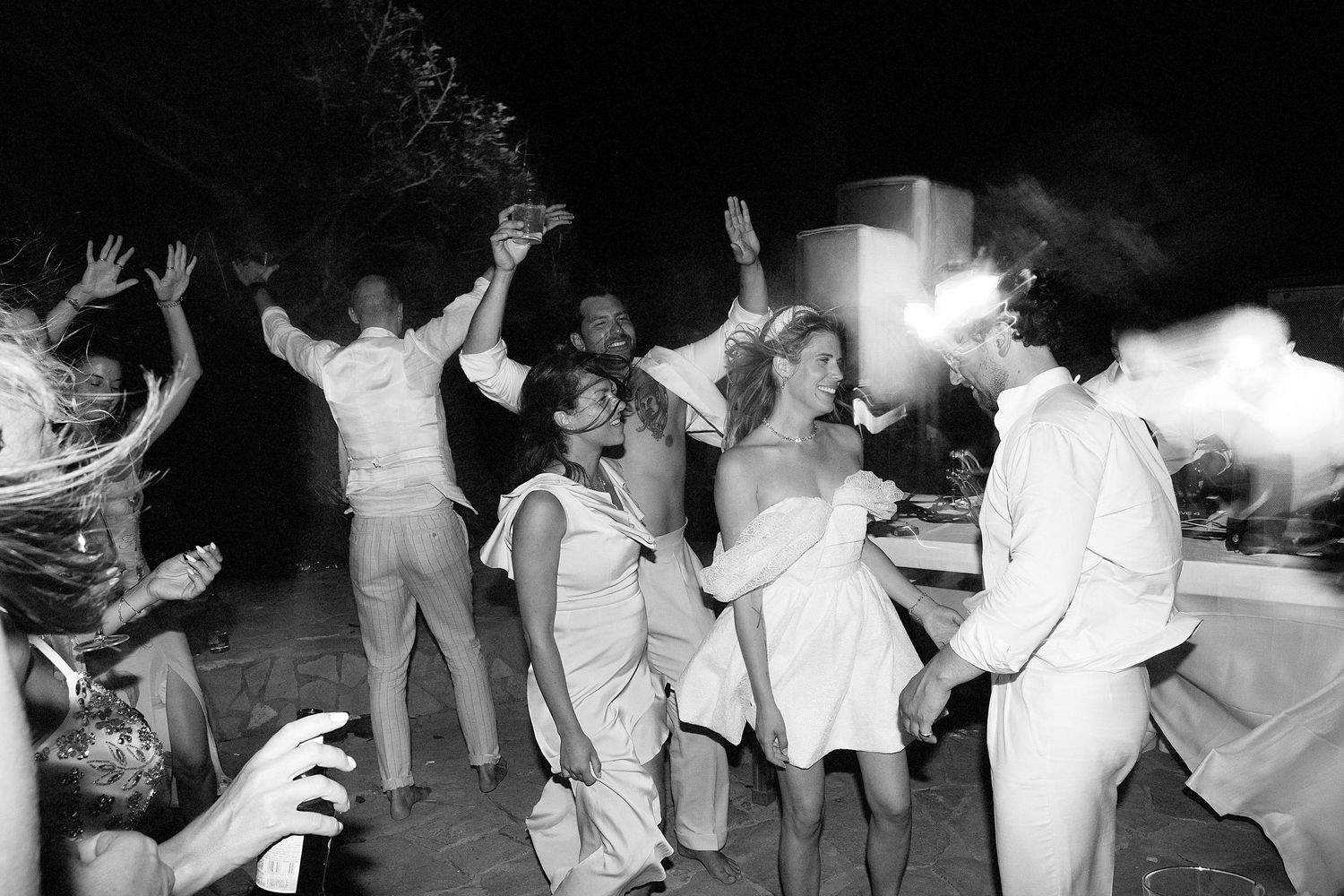 People dancing in a conga line at a party in black and white vintage photograph.