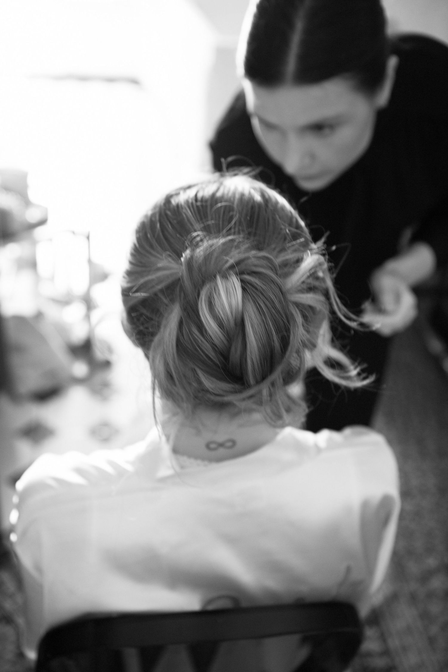 Black and white close-up photo showing an infinity symbol tattoo on someone's arm.