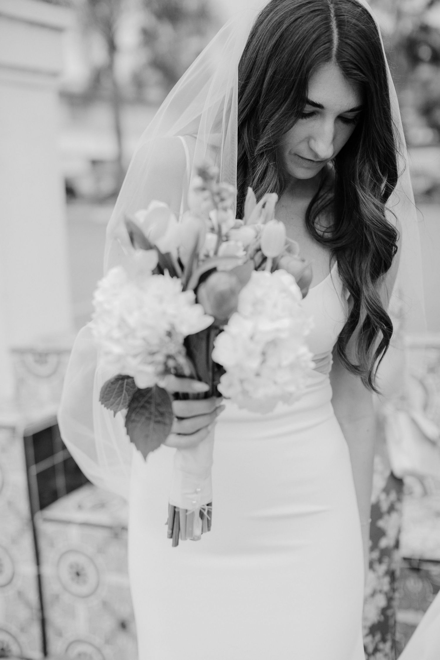 Black and white wedding photography series showing bride in elegant white dress holding floral bouquet.