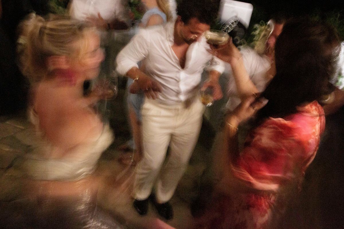 Blurred motion photo of people dancing energetically at a lively party or wedding reception event.