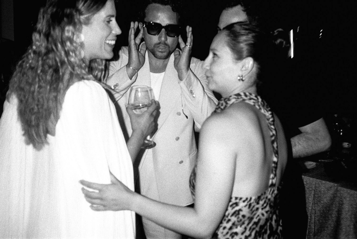 Black and white photo strip showing four candid party scenes with people dancing and socializing at a celebration.