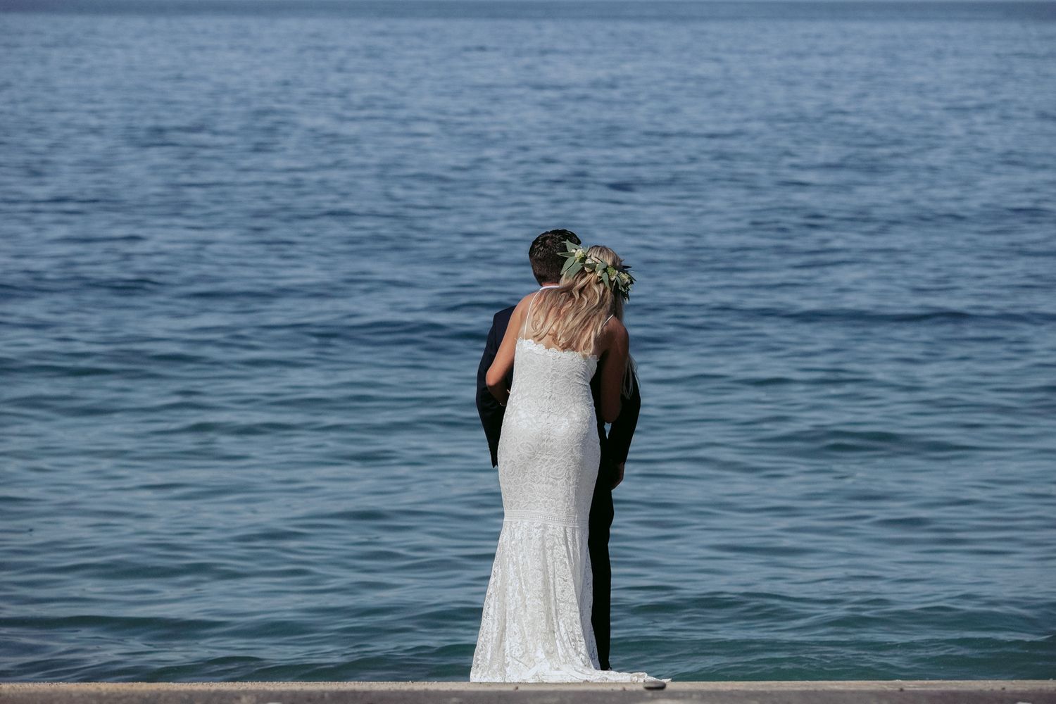 A couple in wedding attire shares an intimate moment by the ocean during their beach wedding ceremony.