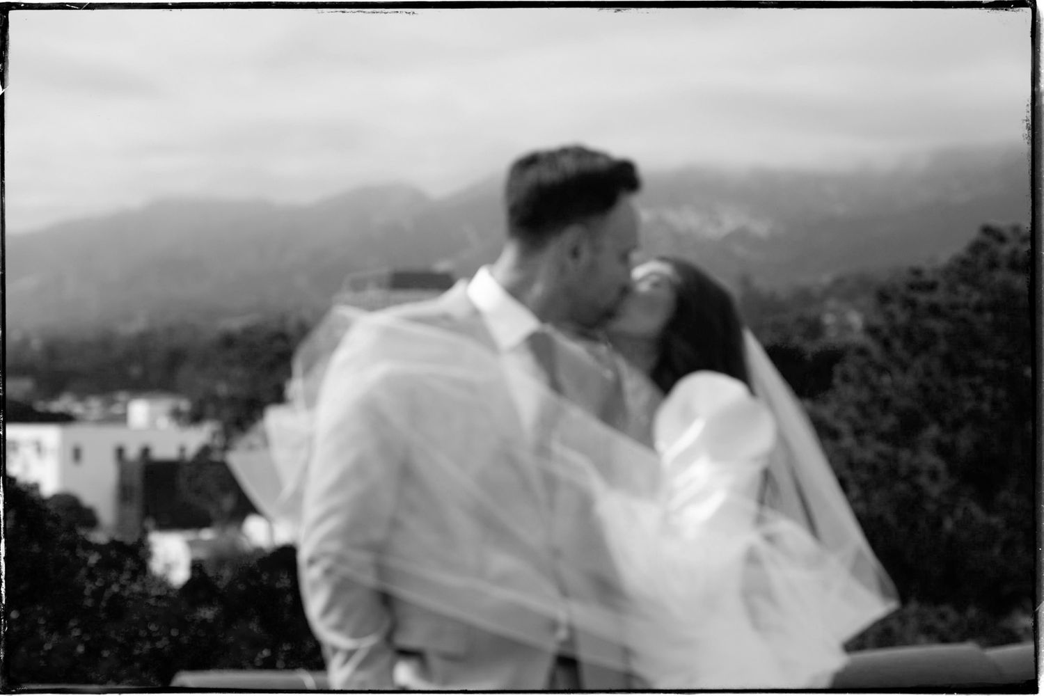 A black and white panoramic view shows a series of mountain peaks with fog rolling through the valleys.