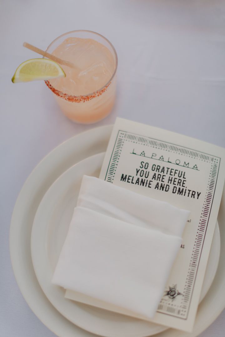 Place settings with pink cocktails and name cards at an elegant wedding reception table.