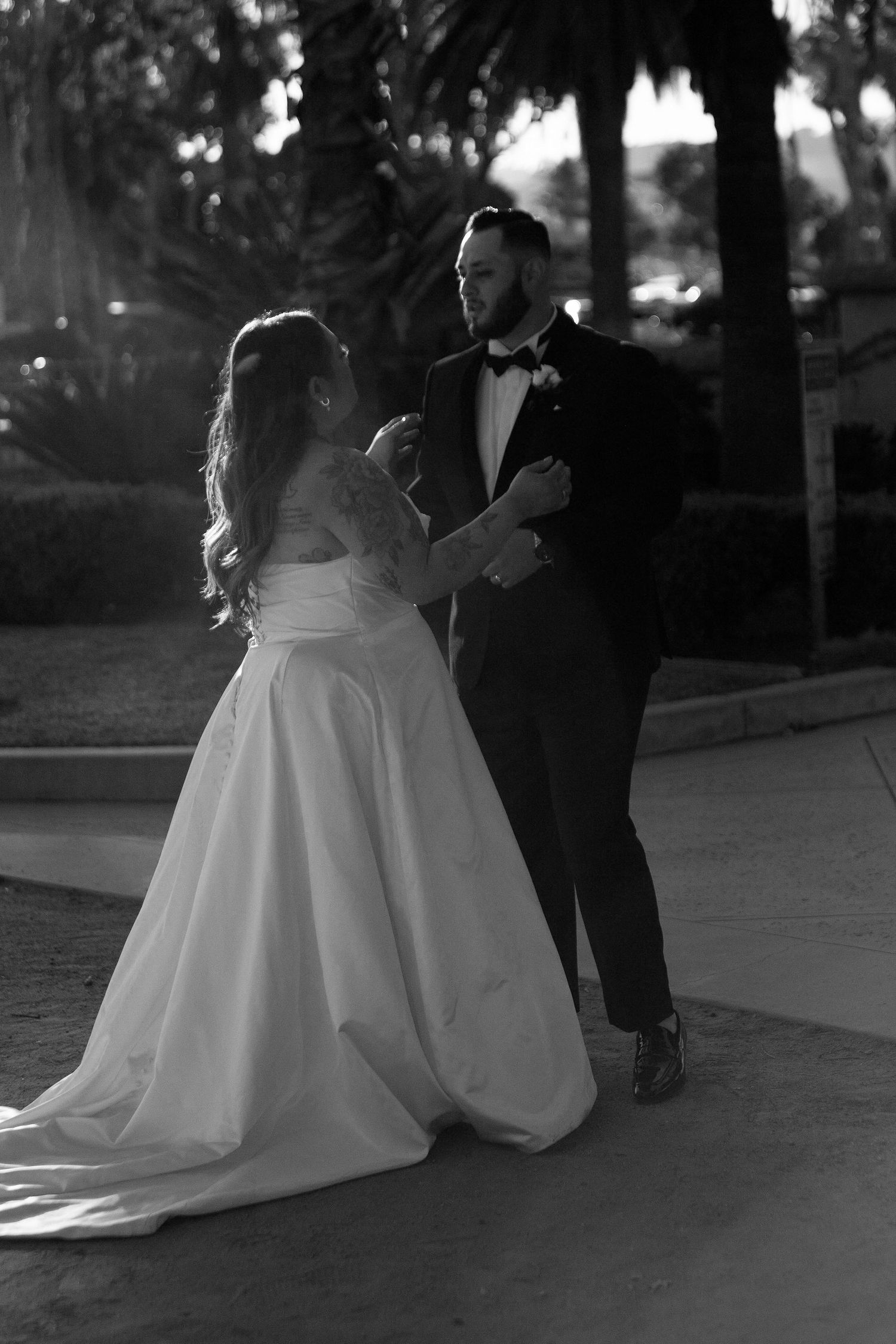 Black and white wedding photo series showing couple in formal attire sitting together on outdoor steps at dusk.