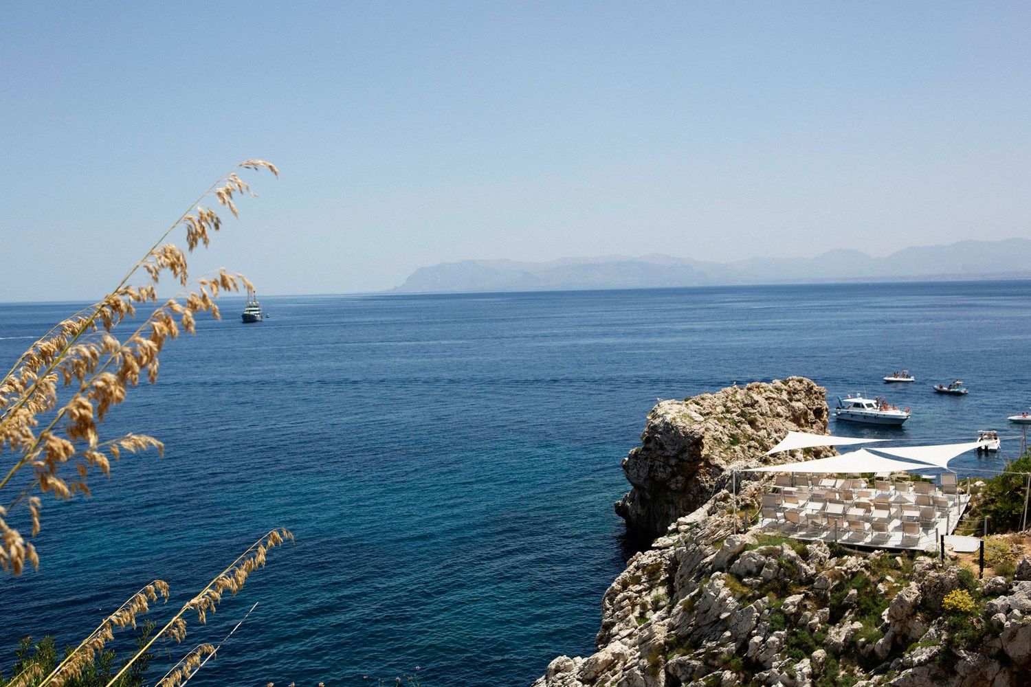 Scenic coastal cliffs overlooking the deep blue ocean with golden sea oats swaying in the foreground.