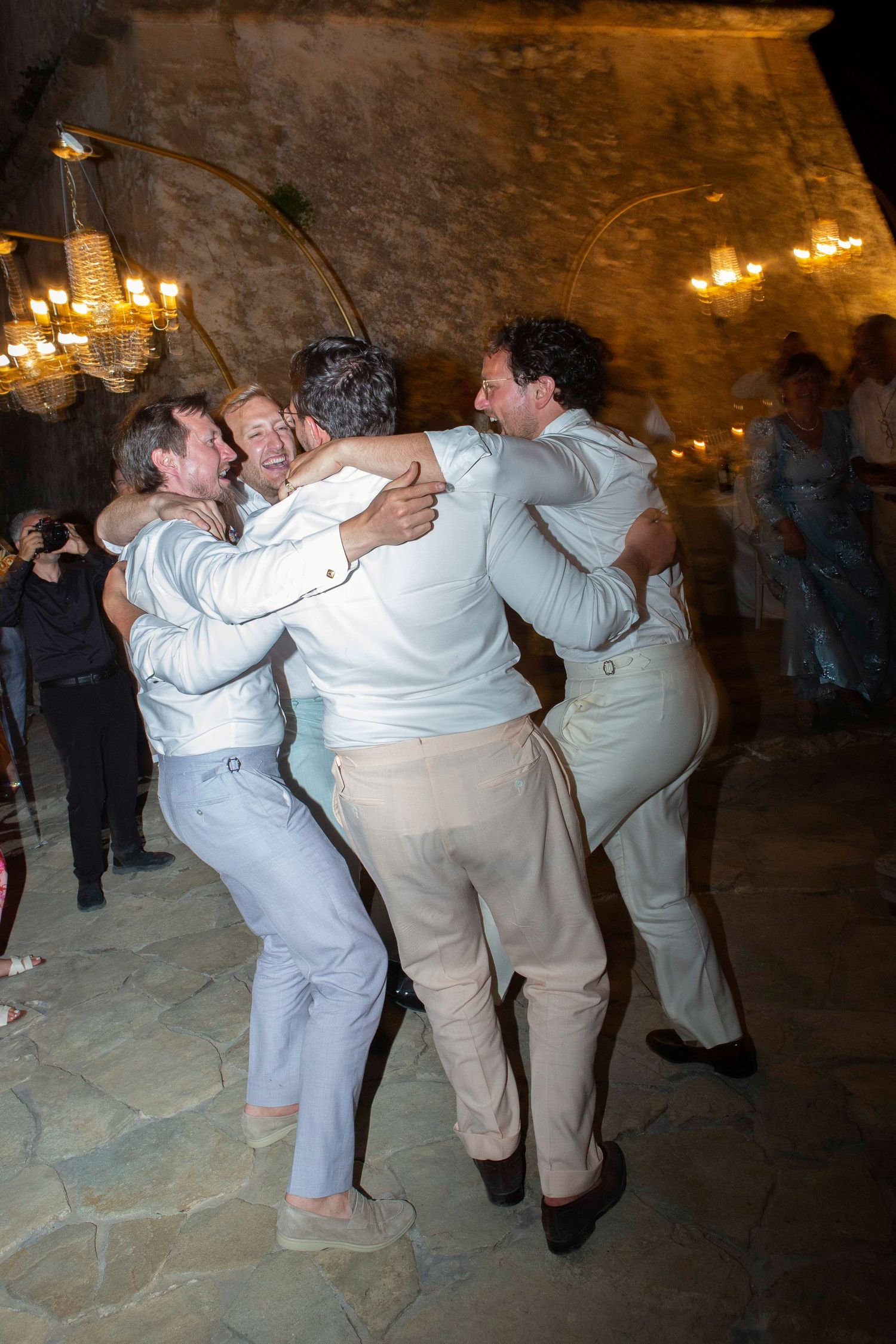 A sequence of dance moves showing people in white and beige attire dancing energetically in a dimly lit venue.