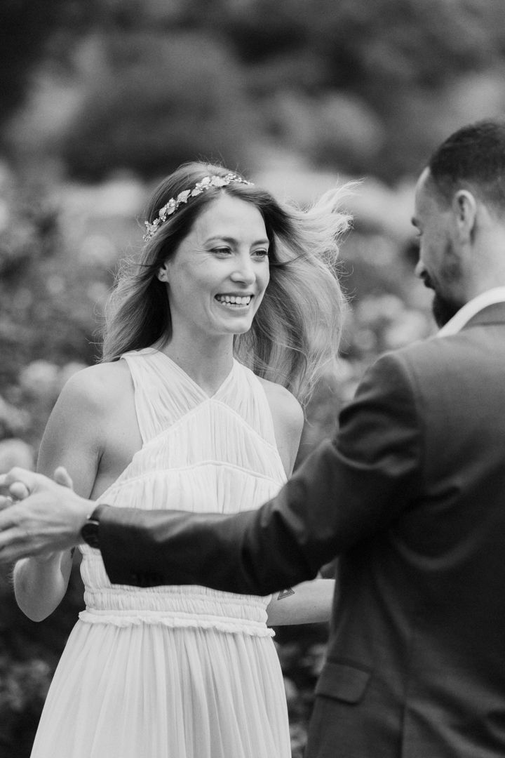 A joyful couple shares a romantic dance moment outdoors in black and white photography.