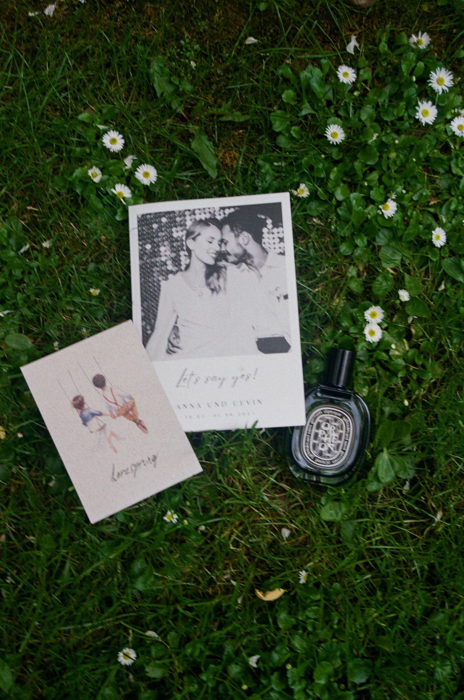 Black and white photographs scattered on green grass with small white daisies blooming around them.
