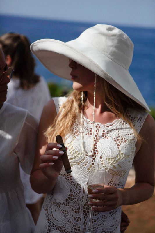 Close-up details of a white lace wedding dress with delicate shell patterns in sunlight.