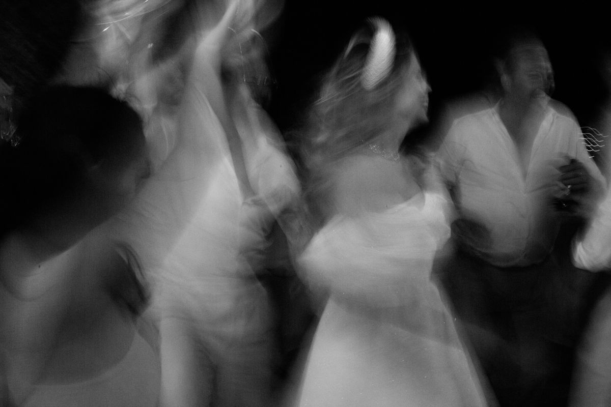 Blurred black and white motion photograph of dancers spinning on a dance floor in ethereal movement.