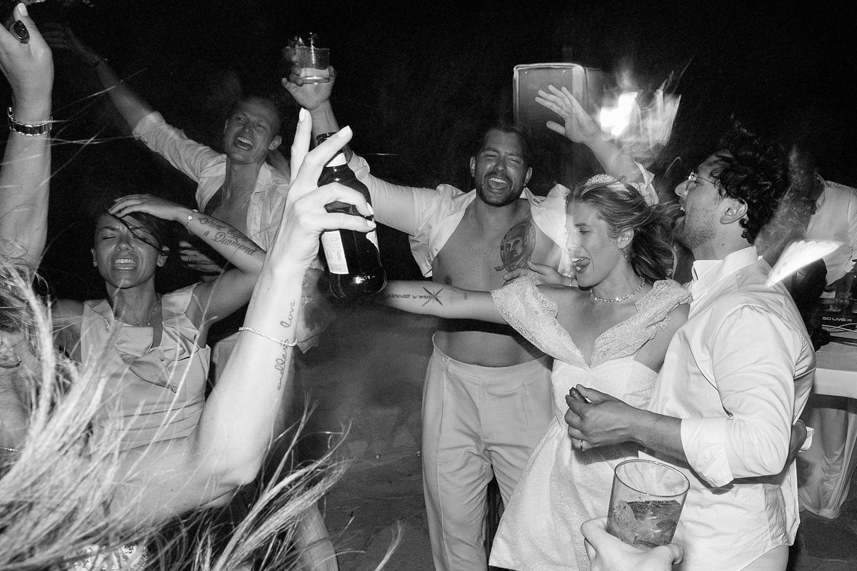 Black and white photo of a crowd dancing and celebrating at what appears to be a lively party or nightclub.