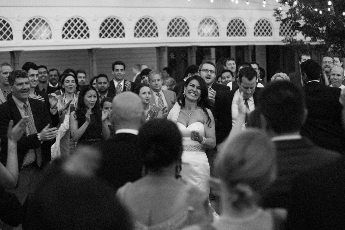 Wedding guests dance and celebrate on a crowded dance floor during an evening reception celebration.