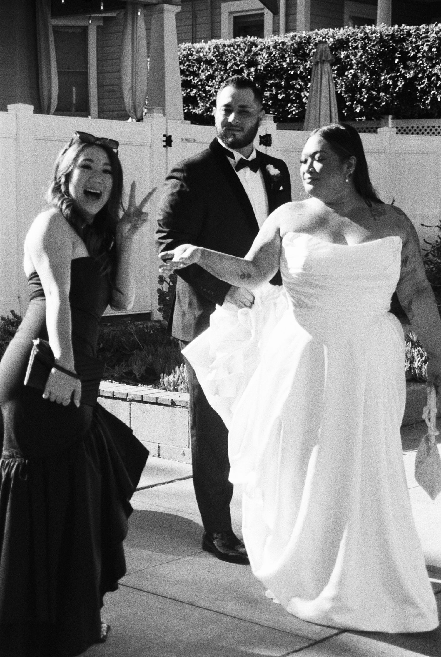 A black and white photo series showing a bride in a white gown and bridesmaids in black dresses sharing joyful moments.