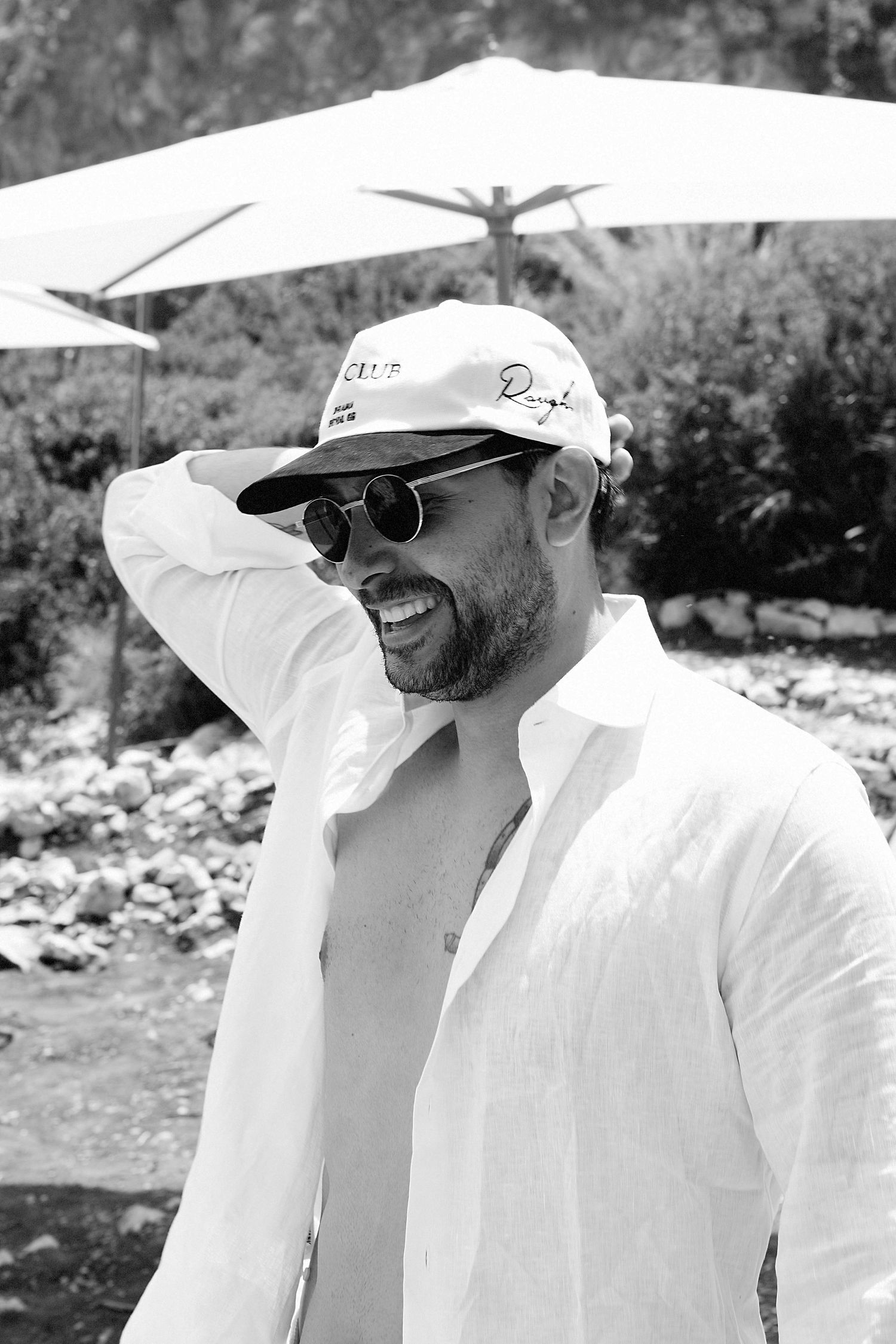 A person wearing a white hat and sunglasses smiles while enjoying a sunny outdoor day.