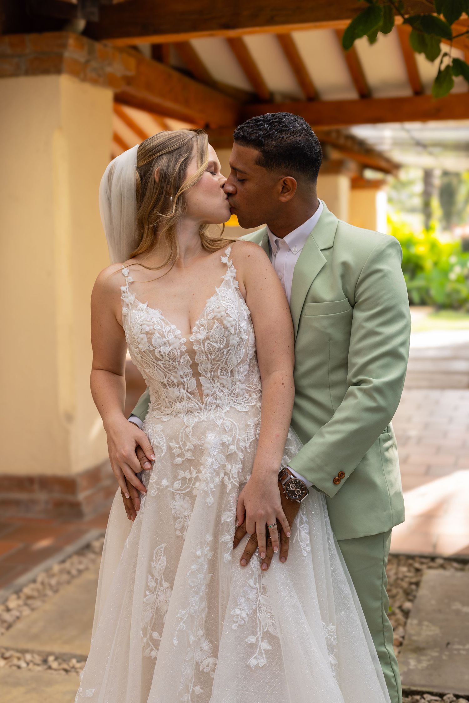 Intimate wedding moment between couple under Spanish-style covered walkway.