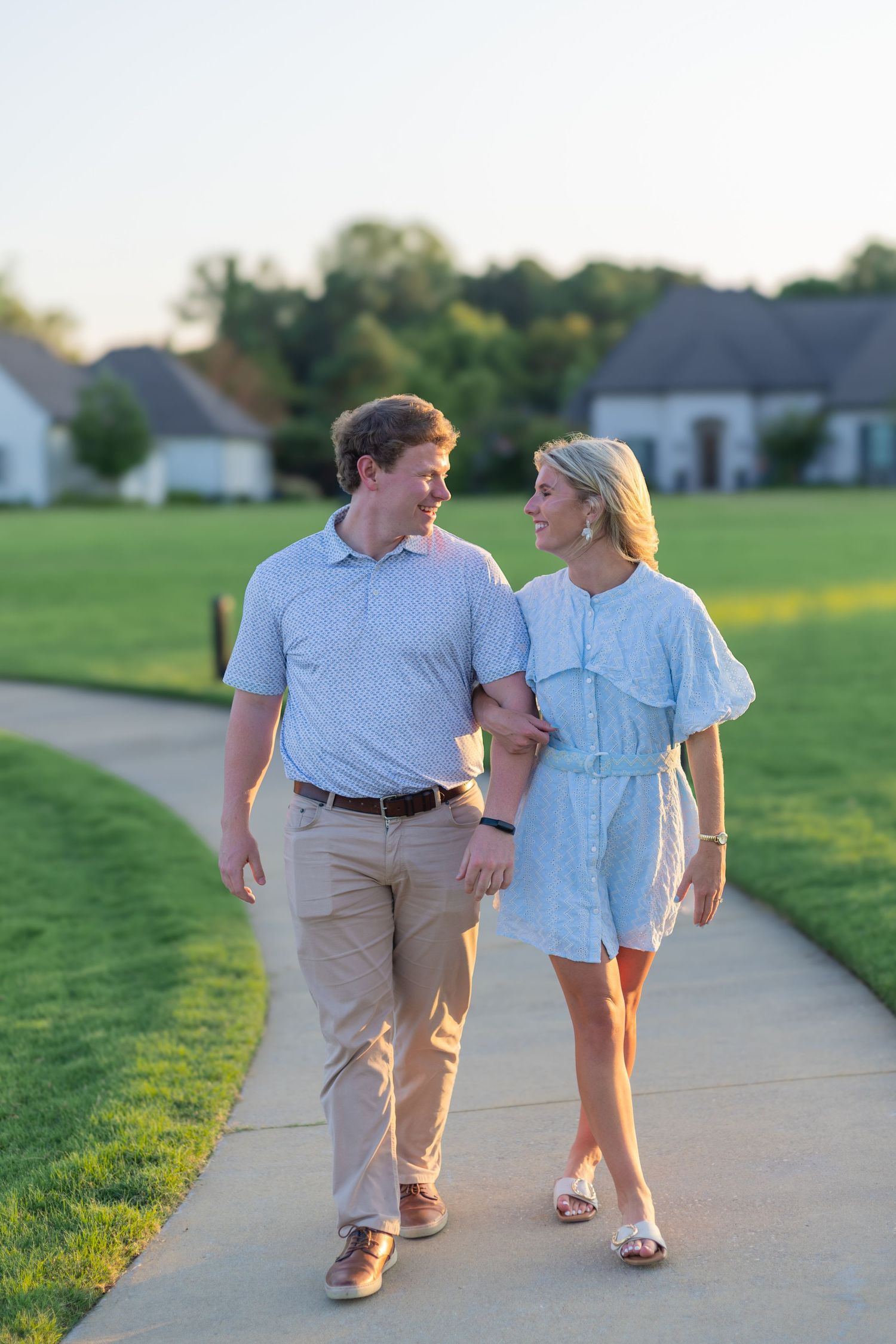 Couple walking together on a paved path during a romantic evening photoshoot.