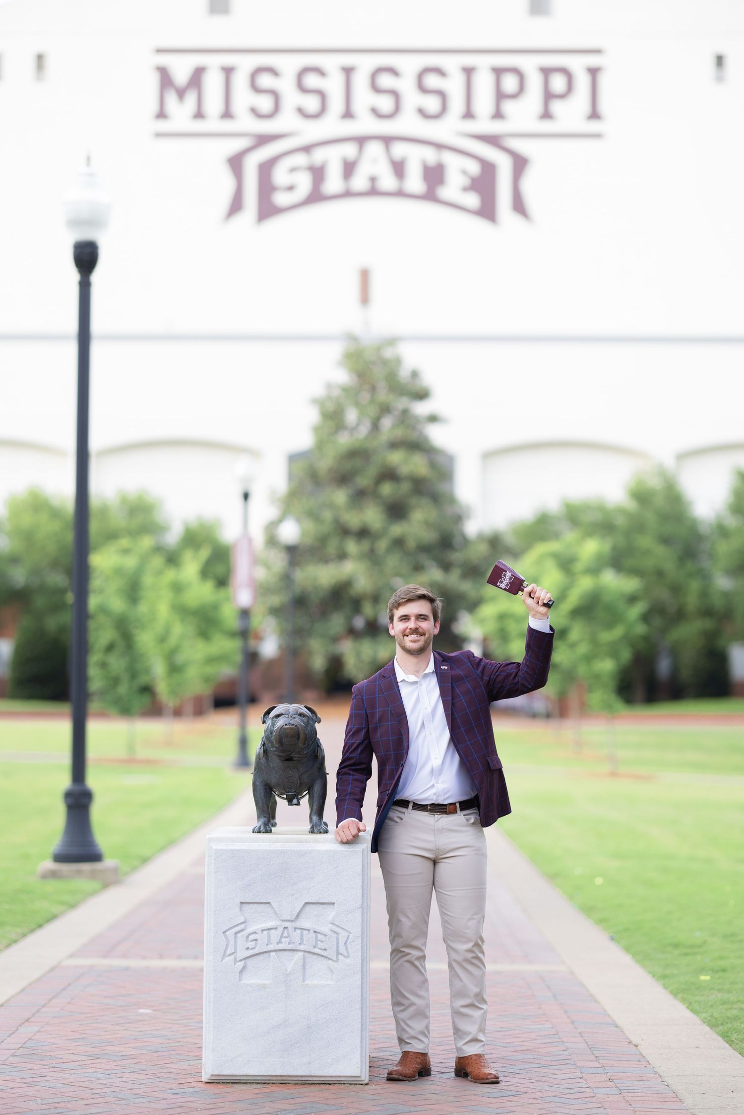 A graduate celebrates near the Mississippi State University sign during a photo session.