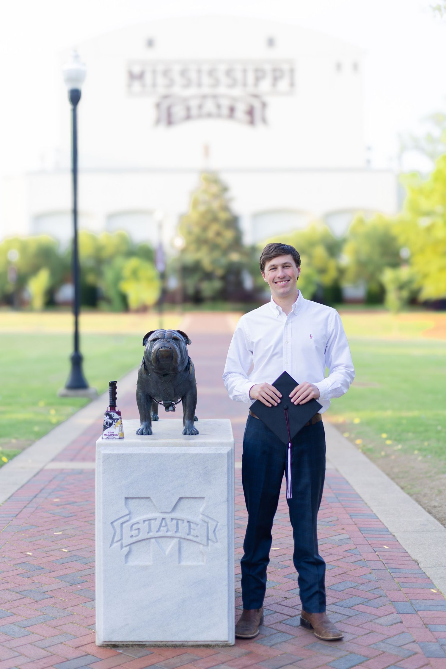 Student poses with Mississippi State University concrete marker on campus walkway.