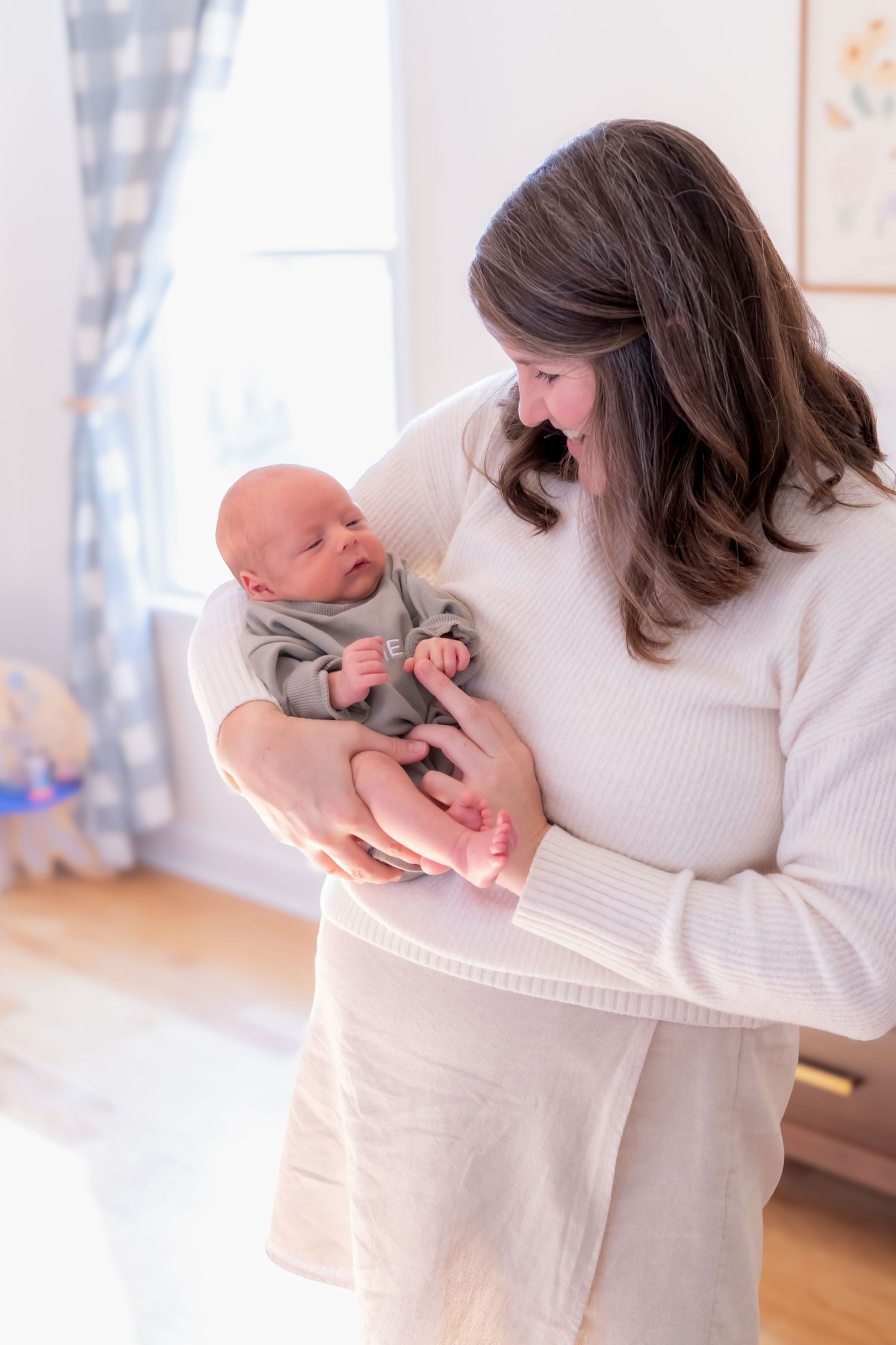 Series showing tender moments with baby in grey outfit being held in white room.