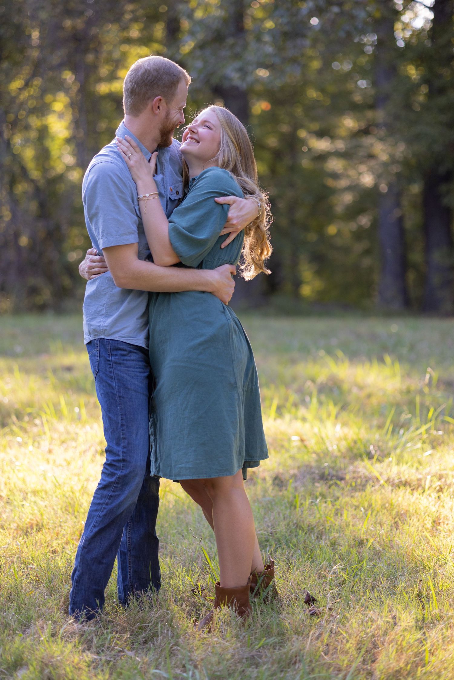 Romantic couple embraces in a sunlit meadow during golden hour photo session.
