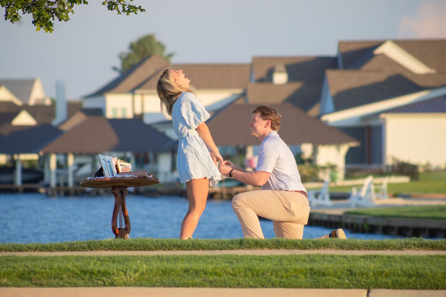A couple walks together on a paved path in a grassy neighborhood setting at sunset.