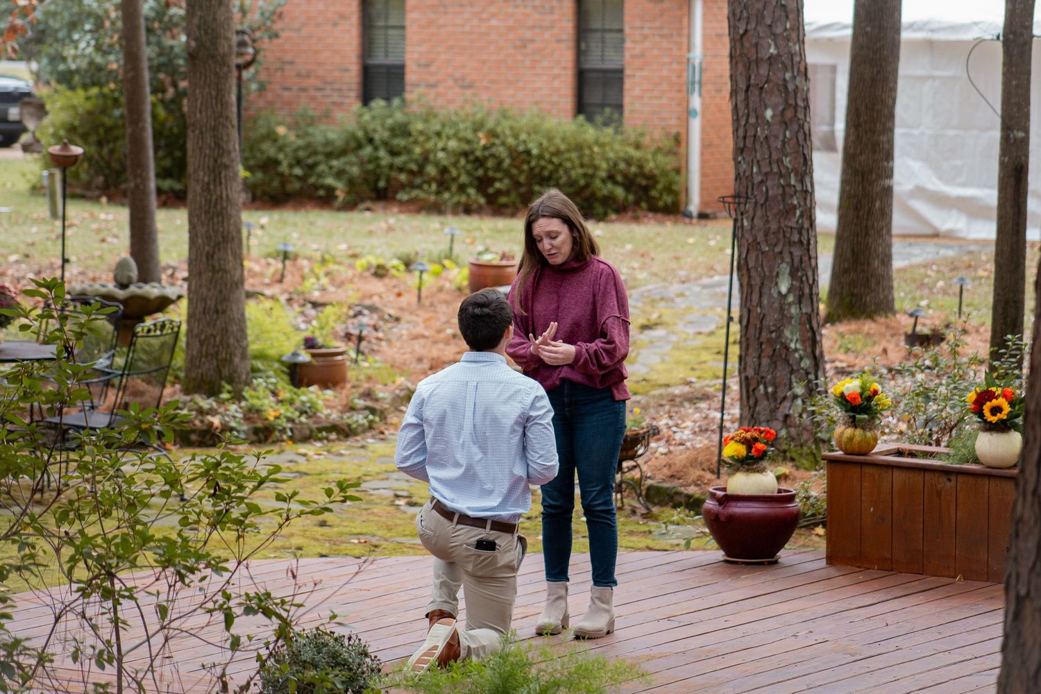 A couple shares a special moment on a brick-lined wooden deck with fall decorations.