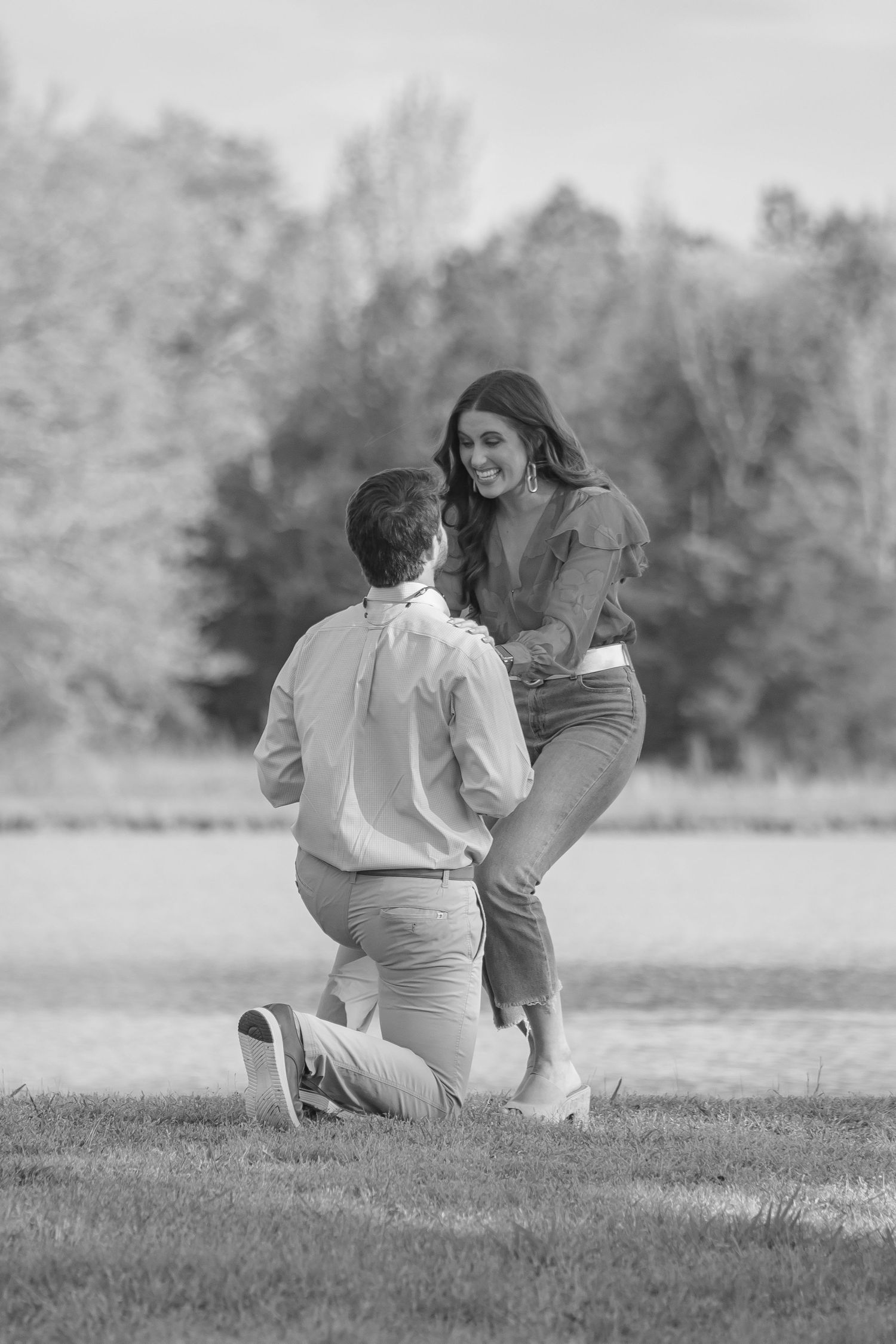 Black and white photo of a romantic proposal in a scenic outdoor location.