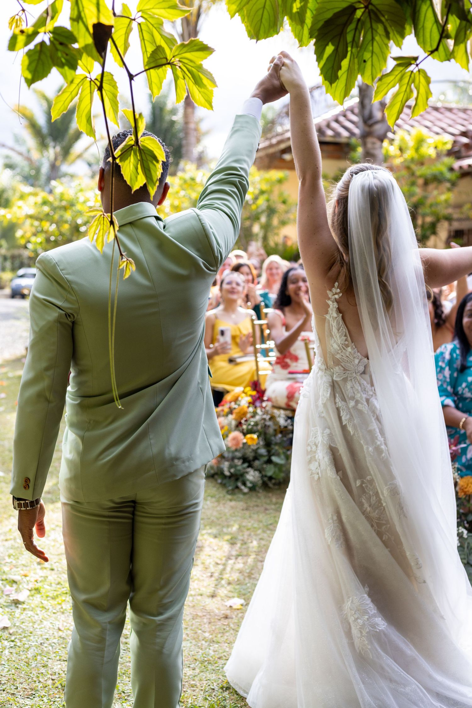 Newlyweds dance together at outdoor reception with bride's veil flowing.