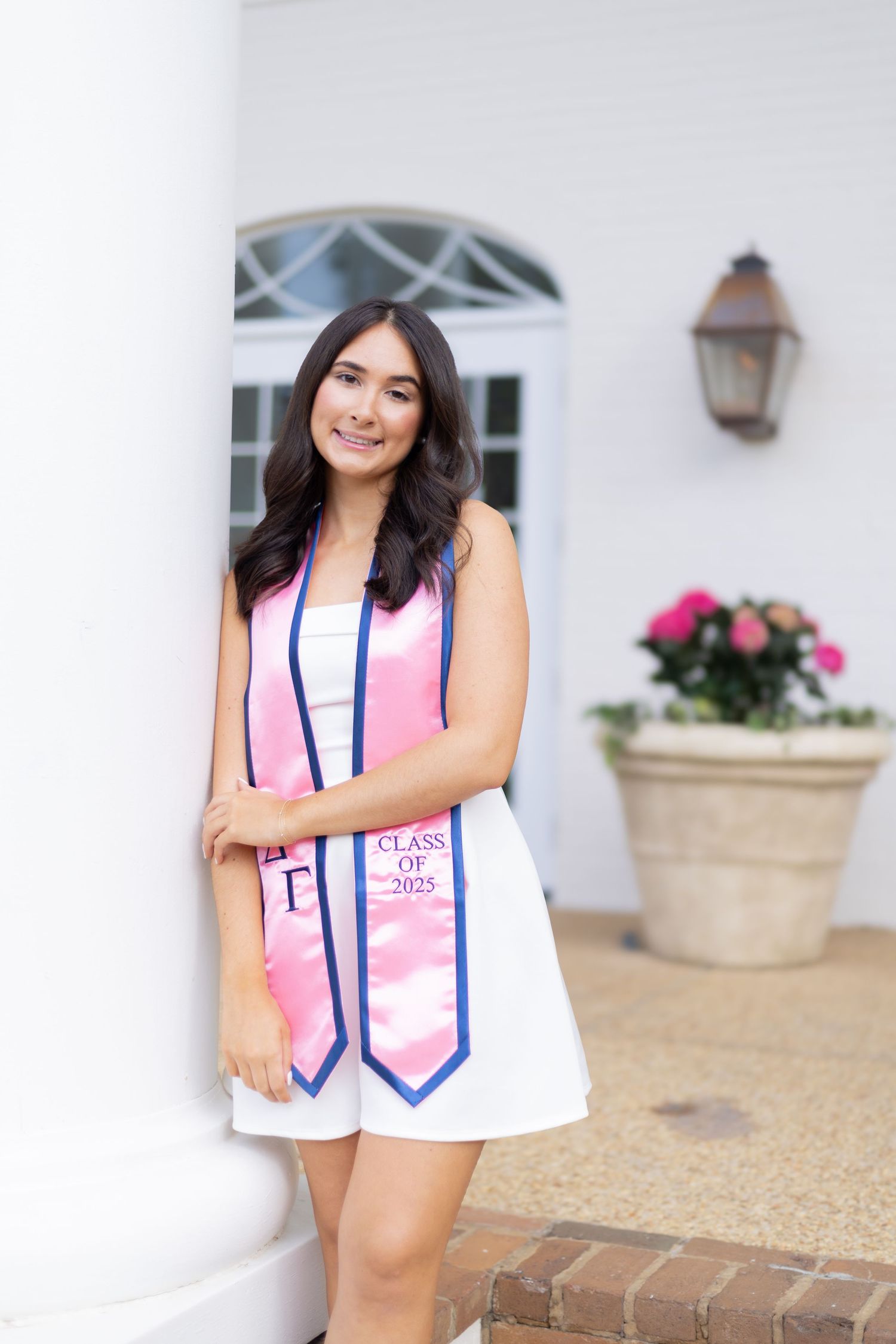 Senior portrait with decorative stoles against white columned building background.