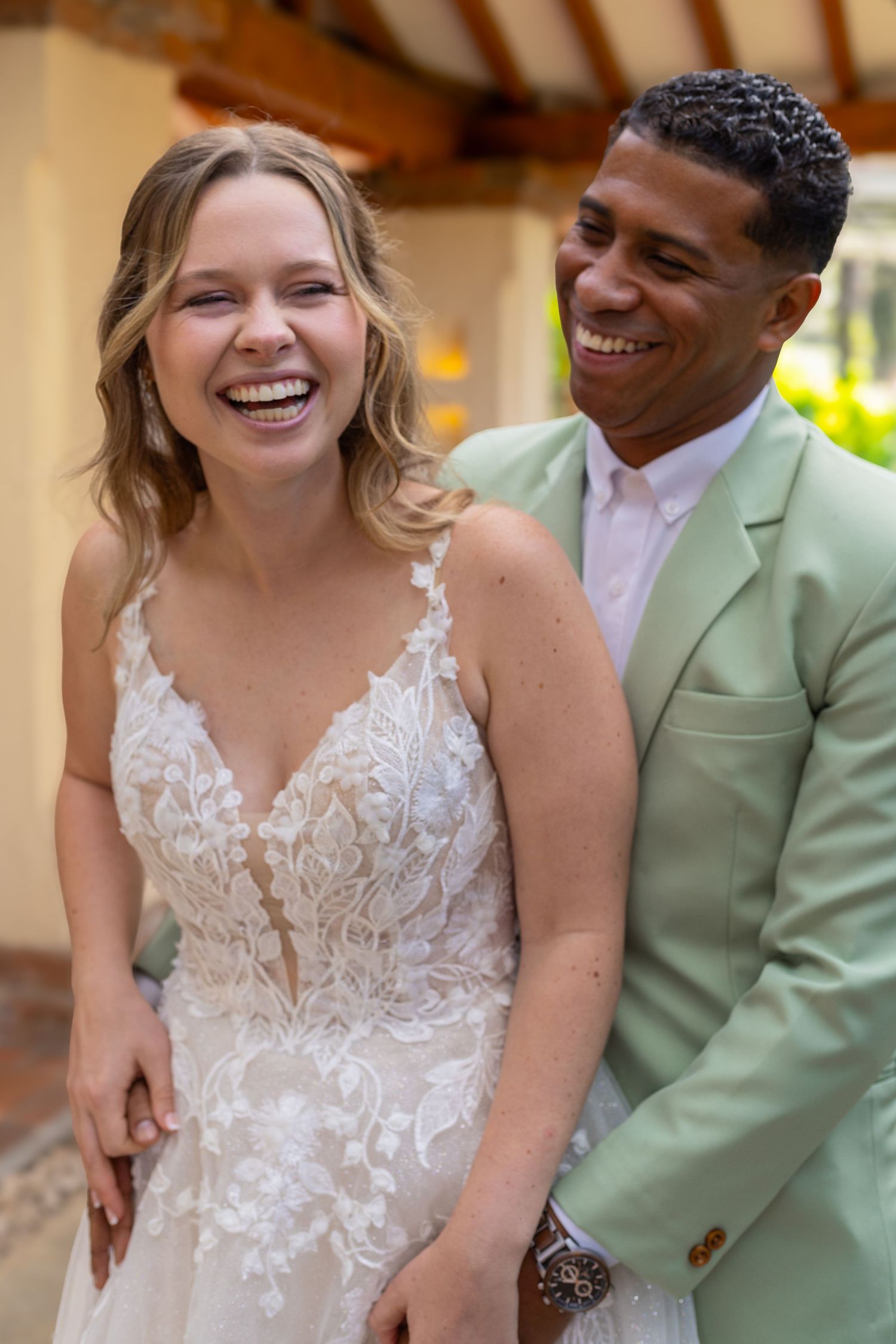 Candid wedding photo showing genuine laughter between couple in garden setting.