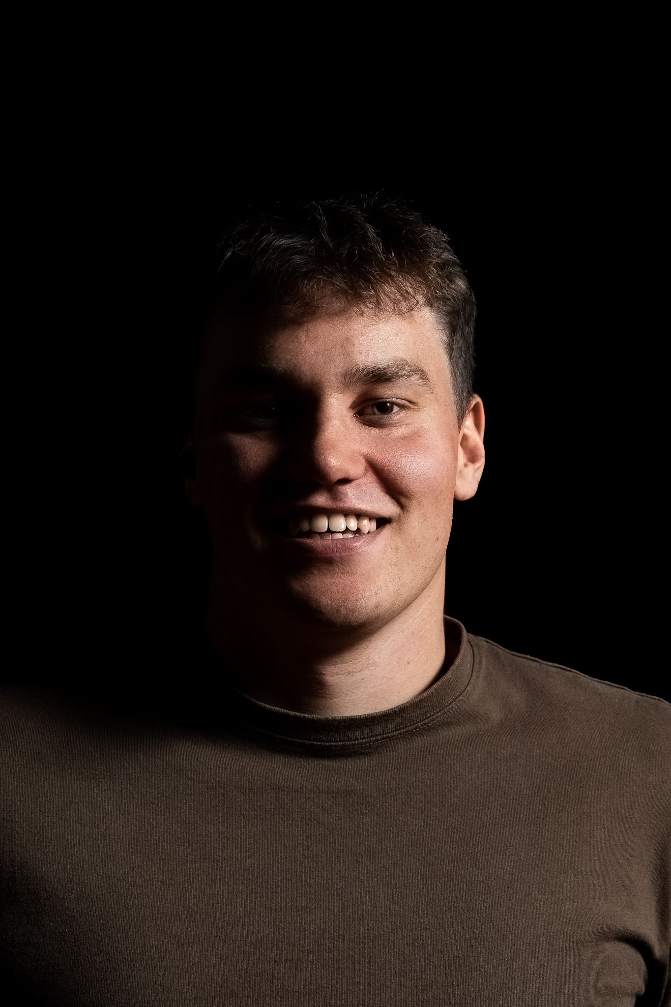 A series of six dark portrait photos showing a person's smile gradually appearing from left to right in dramatic lighting.