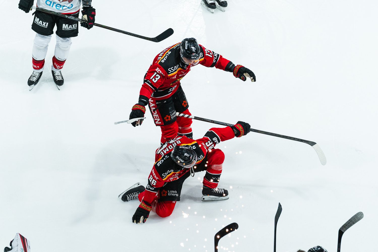 Two hockey players in red jerseys collide on the ice during an intense game moment.