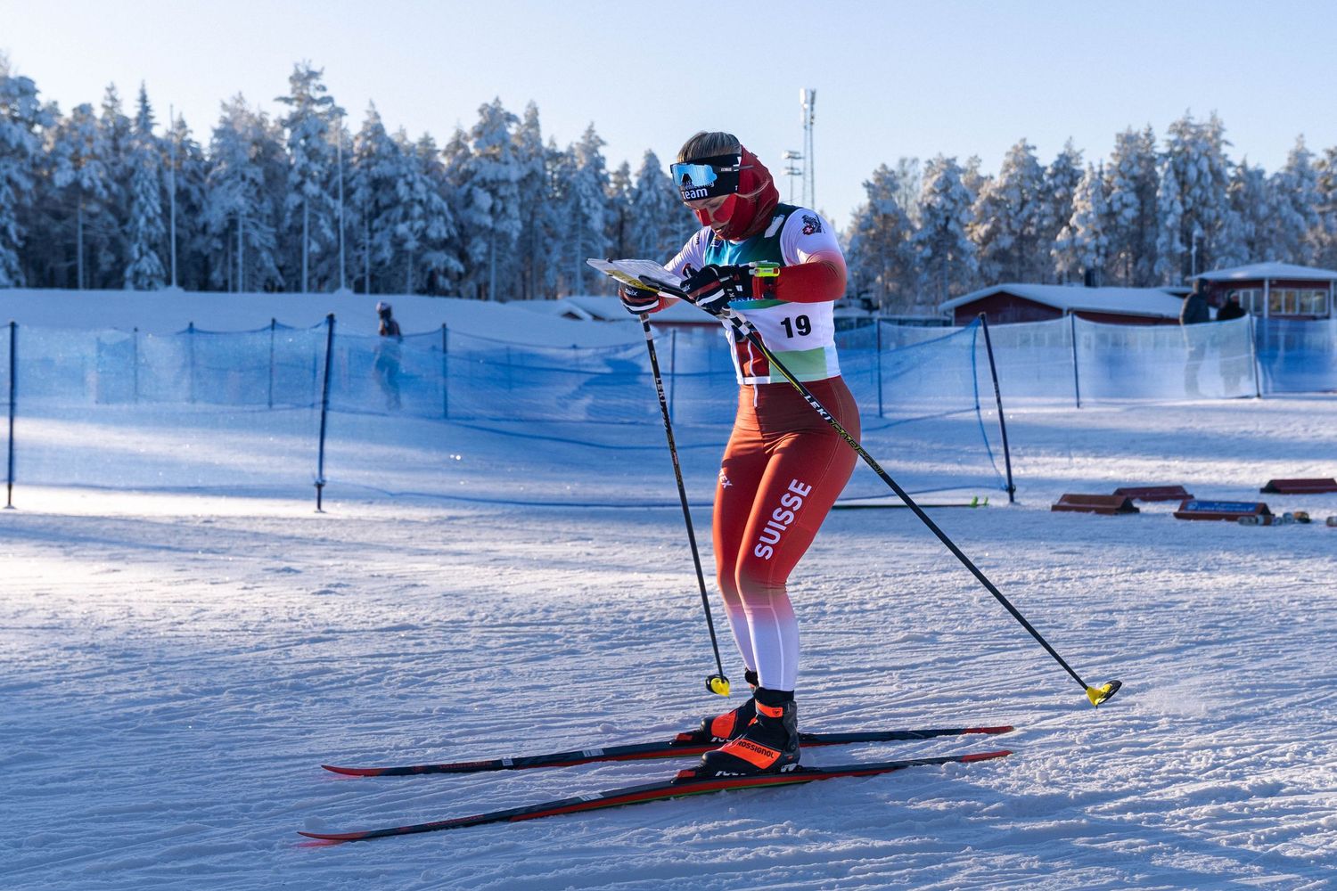 Cross country skier glides across snowy terrain with classic Nordic skiing technique in winter landscape.