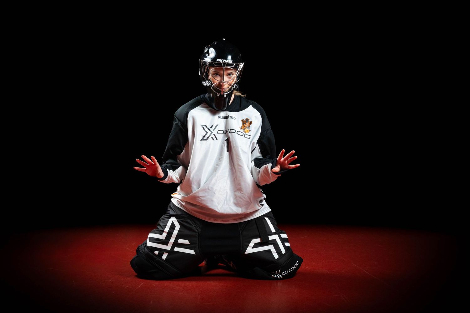 Person wearing black and white clothing sits on red floor in dramatic lighting sequence.
