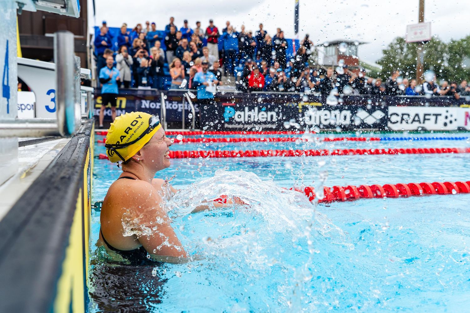 Competitive swimmers race in multiple lanes at an outdoor swimming pool during a championship meet.