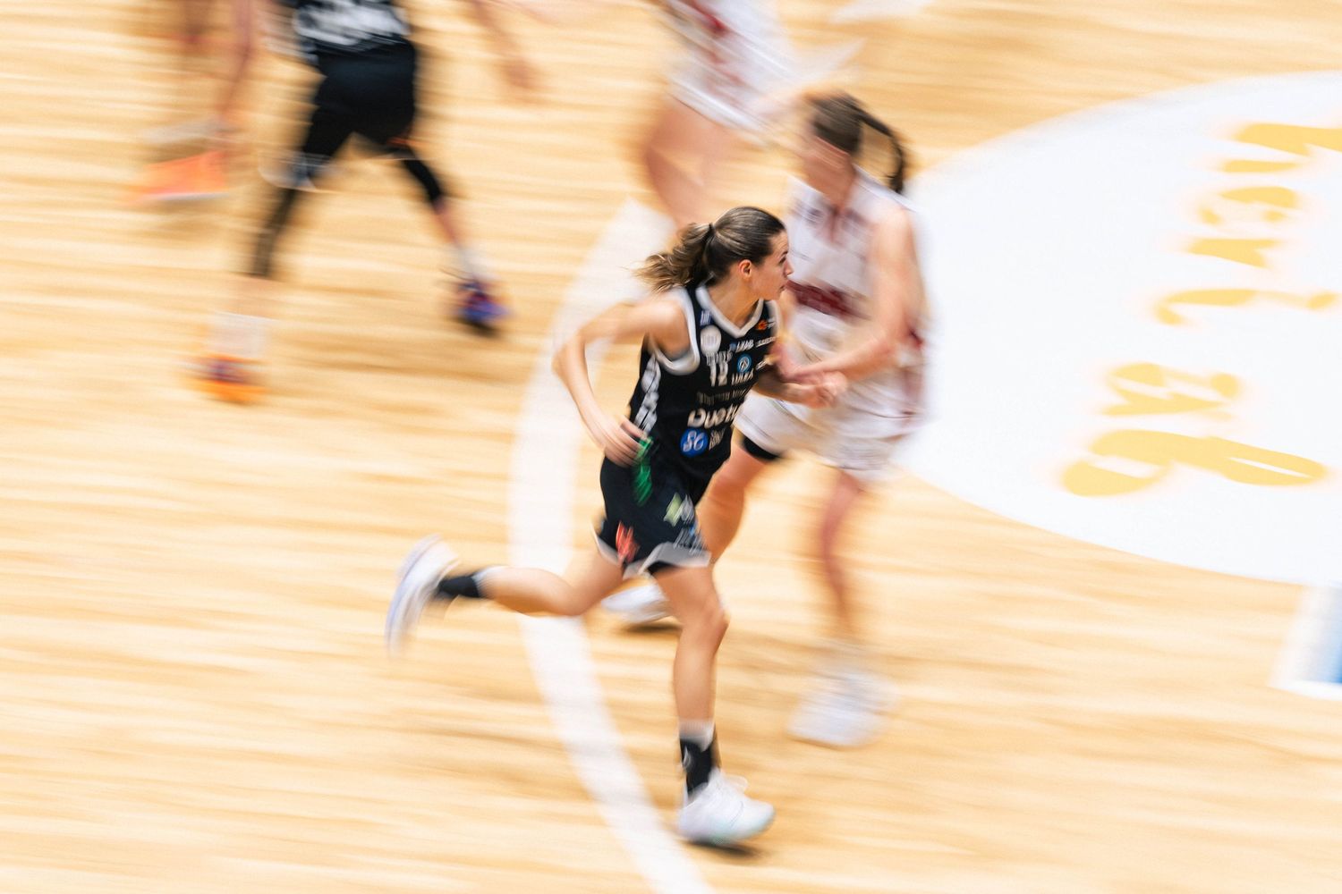 Motion blur of basketball players in action during an intense game on a wooden court.