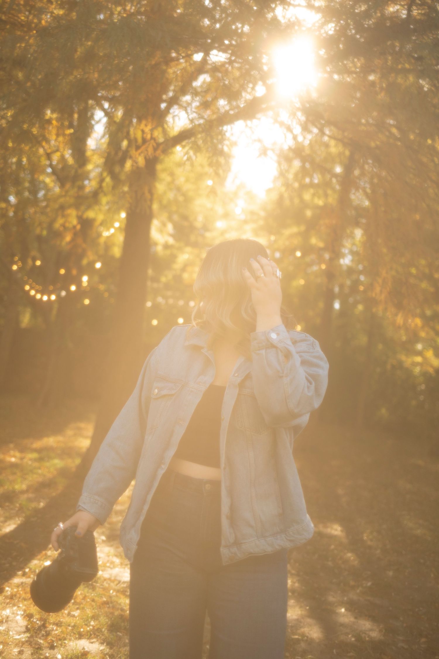 Silhouetted couple embracing in golden sunlit forest with magical bokeh lighting effect.