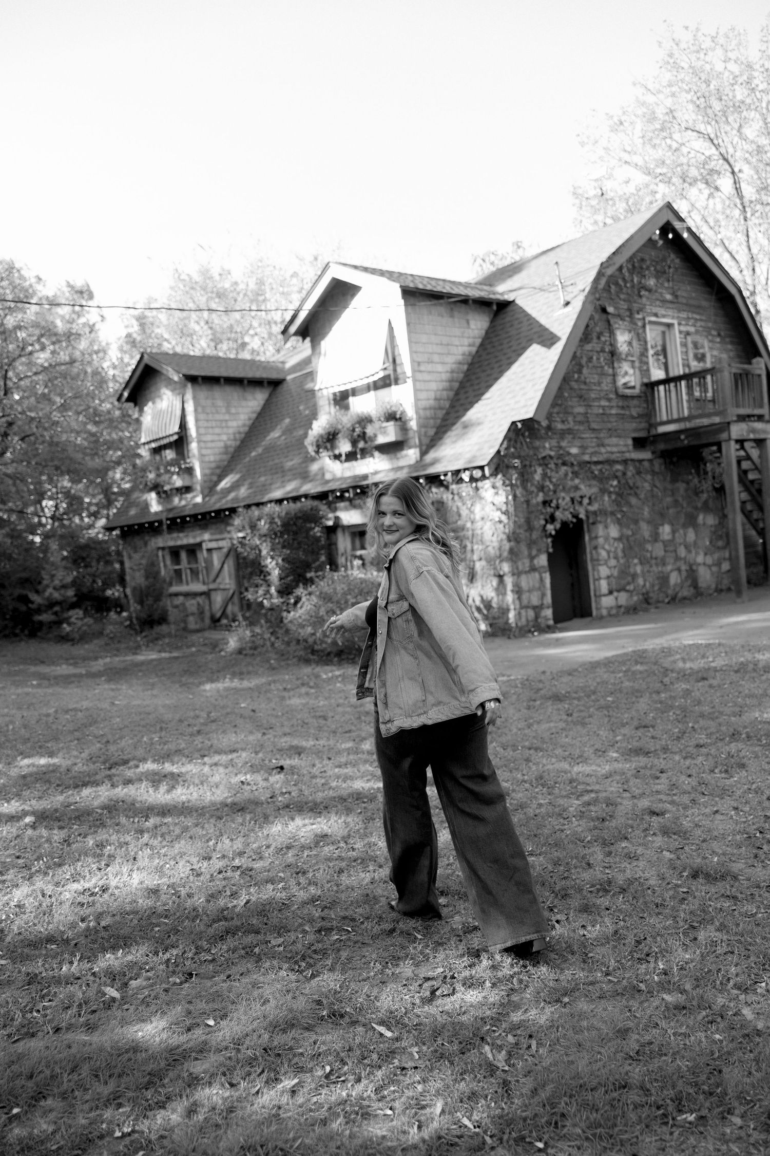 Black and white photo of a person standing in front of rustic stone houses with dormers and steep roofs.