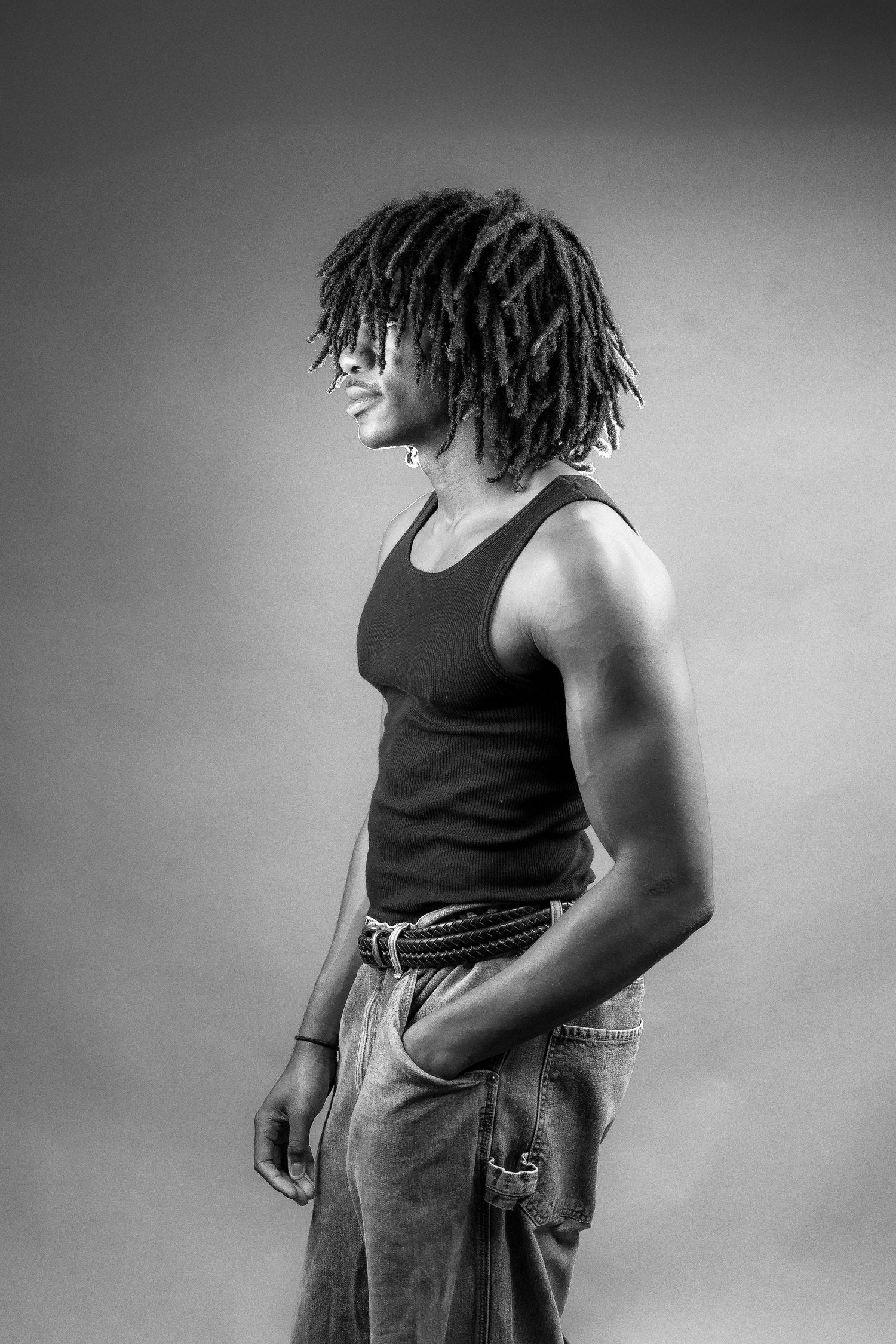 Black and white photos show a figure in a tank top and jeans posing from different angles against a plain backdrop.
