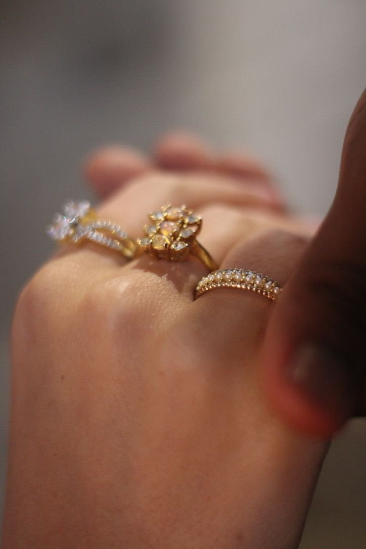Delicate gold and diamond rings displayed on hand with soft focus background.