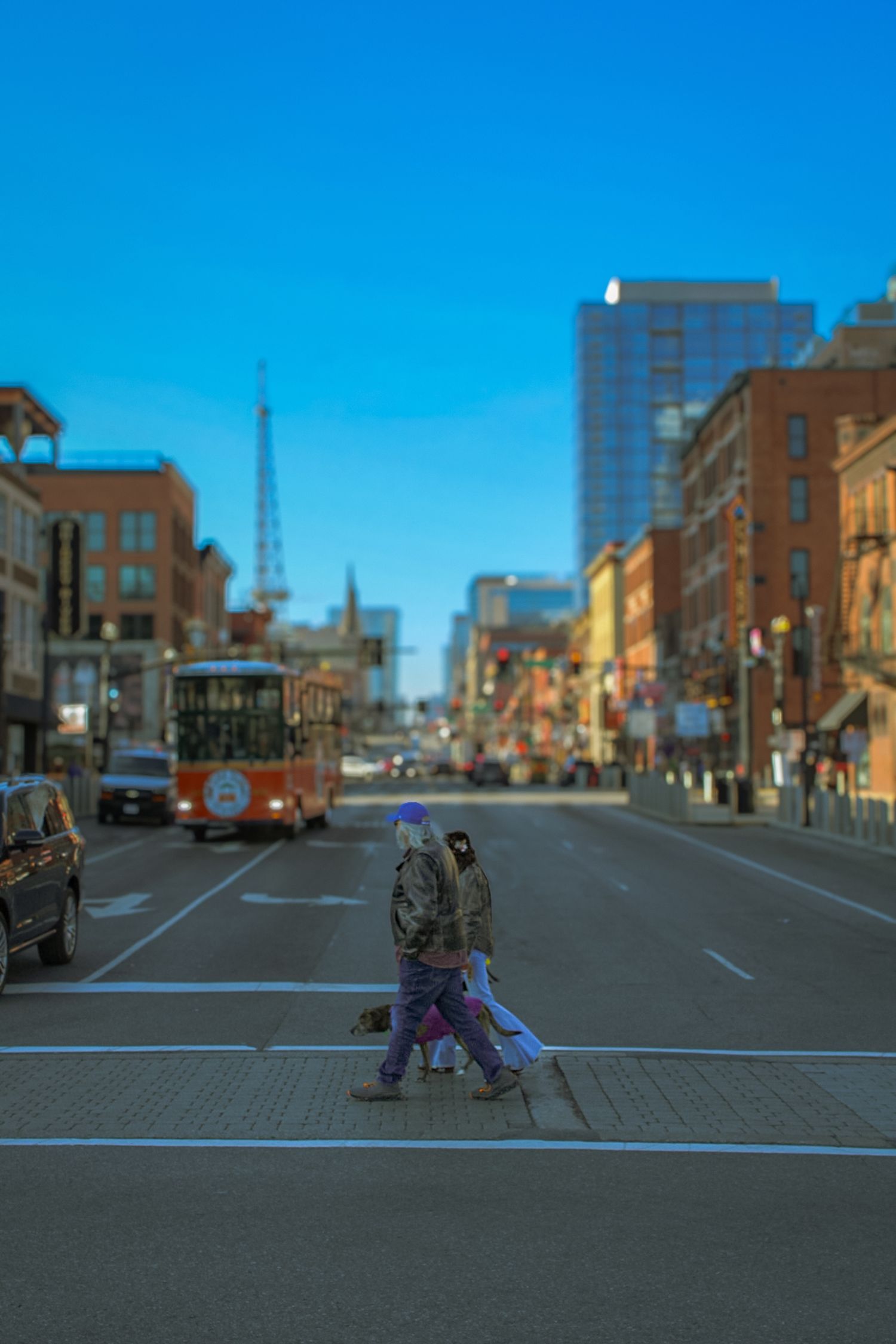 Urban street scene with pedestrians crossing and city buildings in soft focus.